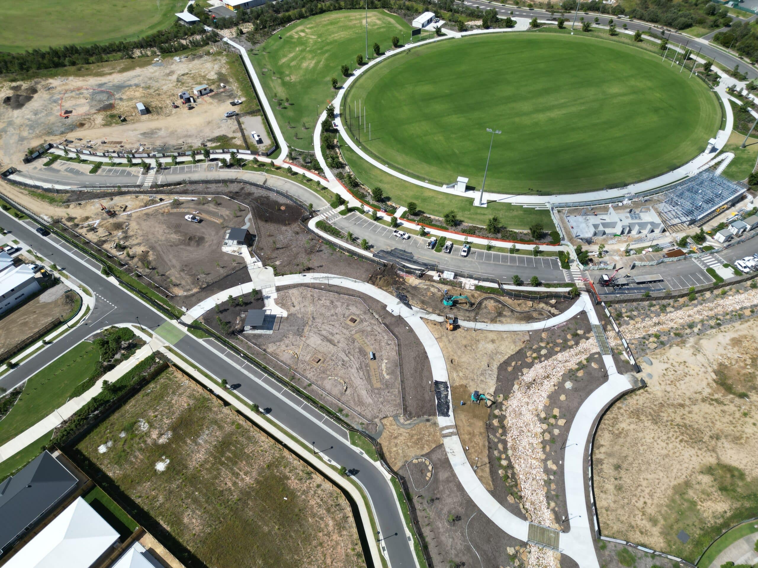Aerial view of a civil earthworks and road construction site beside a sports oval