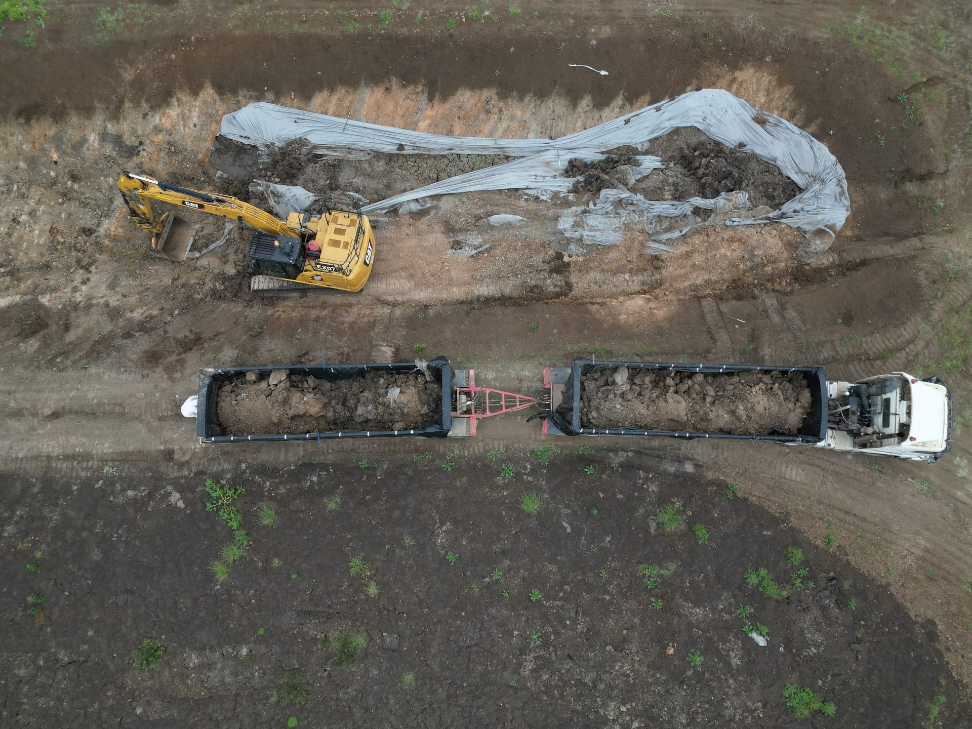 Excavator loading lined trucks, aerial